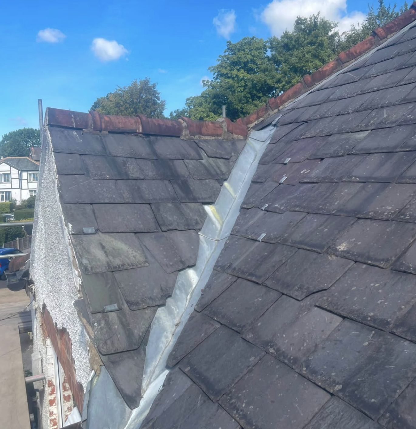 Lead valley running between two slate roof slopes with clay ridge tiles